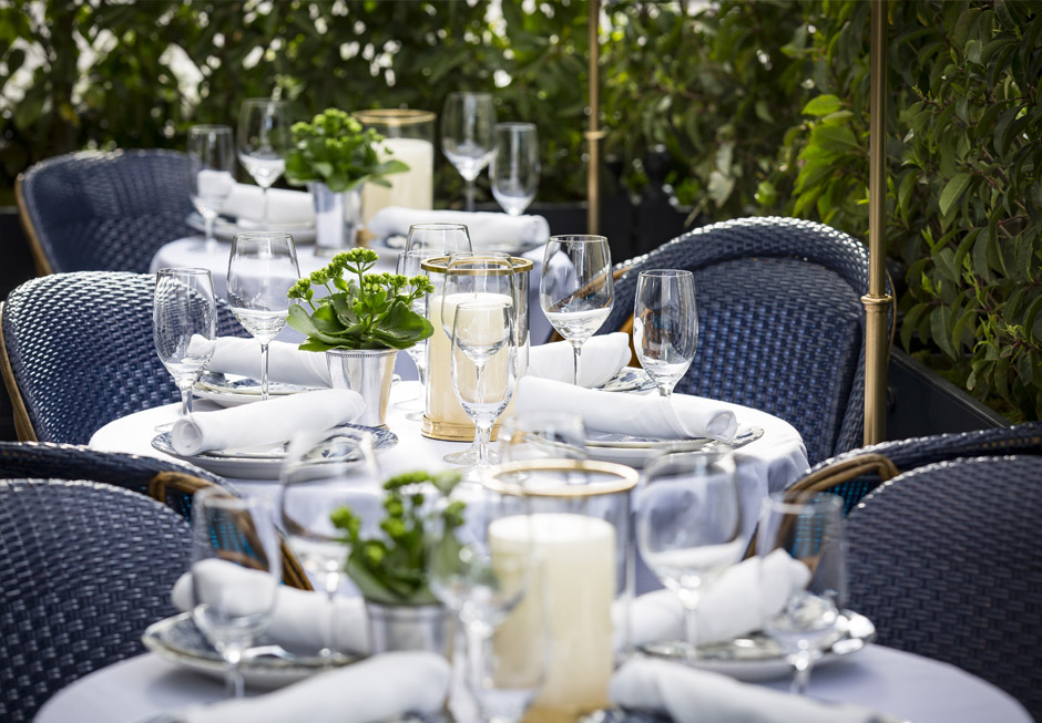 Patio with blue wicker chairs & tables with white tablecloths