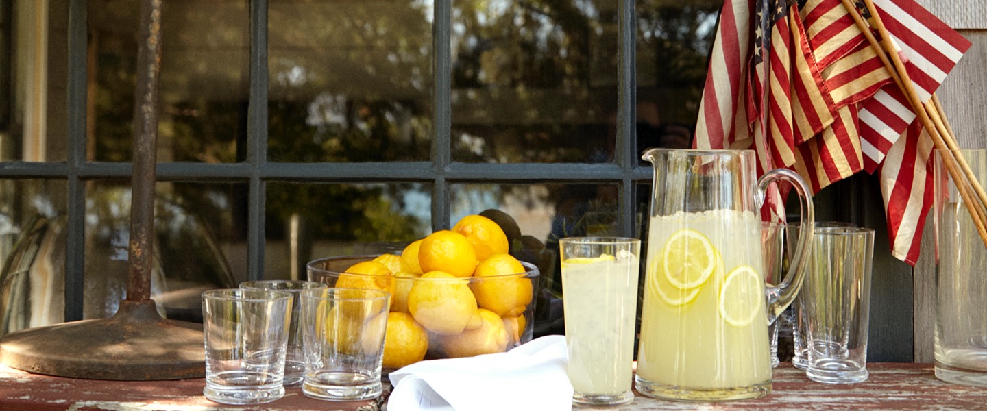 Pitcher of lemonade and bowl of lemons on table outside